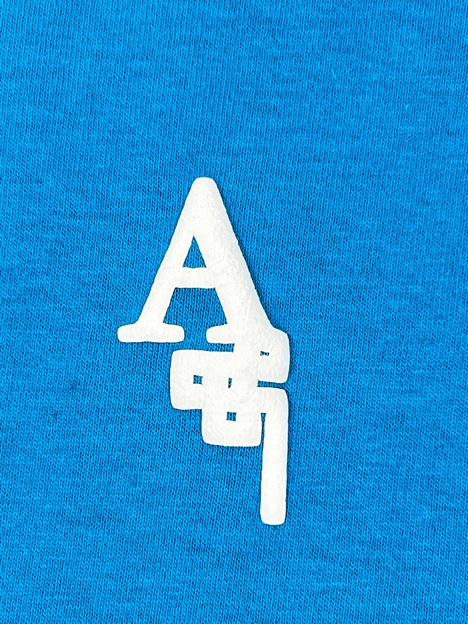The Al Ain AMHX-S818 Majorelle T-shirt Orient by AL AIN features white stylized "A87" letters on blue 100% cotton fabric, made in Italy.