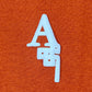 The AL AIN Al Ain AMHX-S820 Almas T-shirt Ambra features a white stylized "A" on orange 100% cotton, with kanji-inspired design elements; proudly made in Italy.