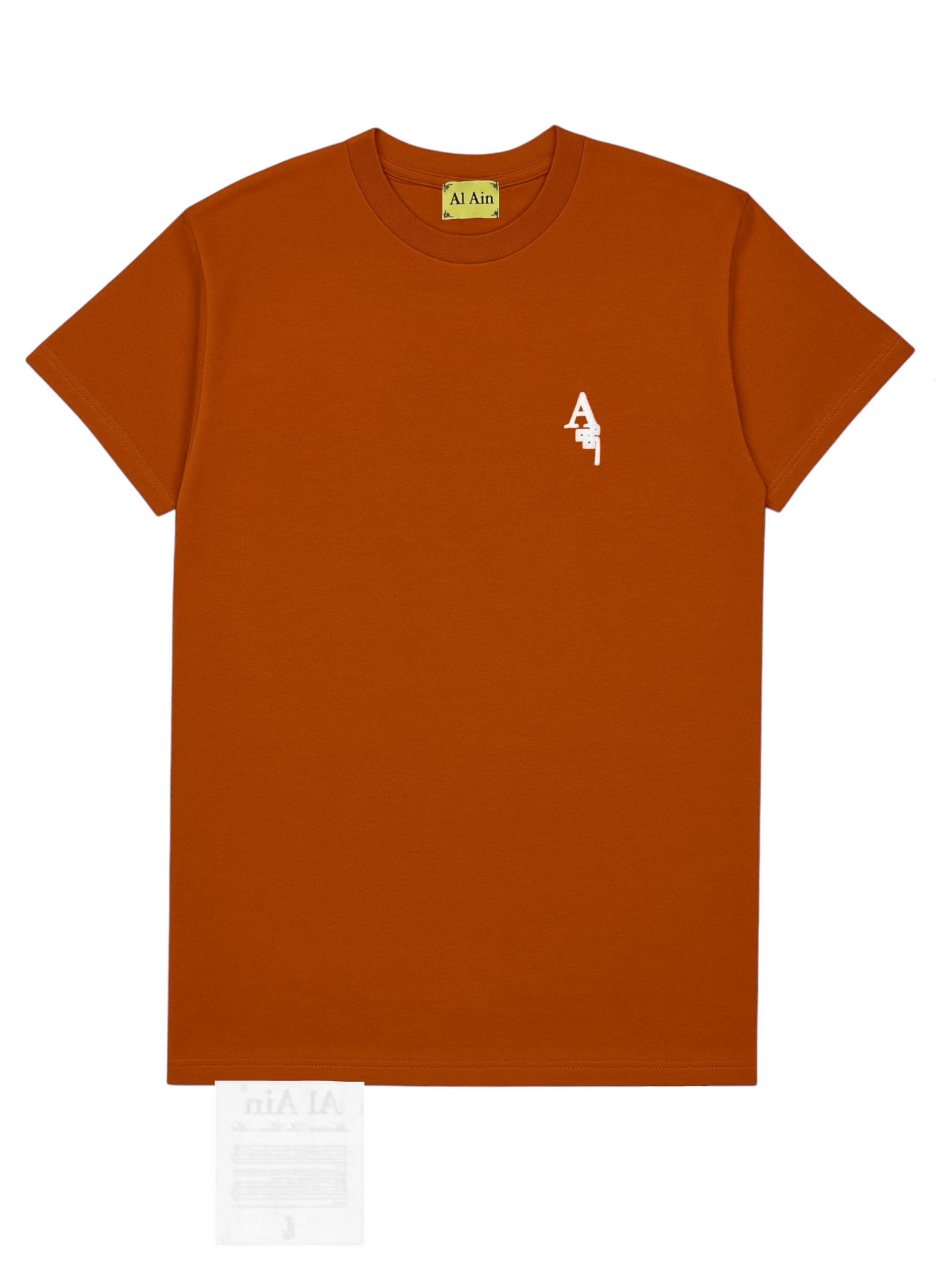 The AL AIN Al Ain AMHX-S820 Almas T-shirt Ambra is a rust-colored Italian-made 100% cotton tee with a small white "A" and Arabic text on the left chest plus an "Al Ain" neck label.