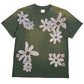 The ALCHEMIST BLOCK PRINT S/S TEE in Moss Green is a vintage-washed graphic t-shirt adorned with large, abstract white flower designs scattered across the front.