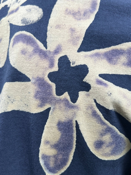 Close-up of the ALCHEMIST BLOCK PRINT S/S TEE NIGHTFALL BLUE, featuring abstract flower prints in white and light purple on a dark blue background, with a vintage washed finish.