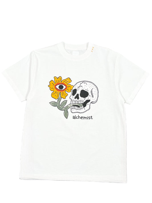 The Alchemist Floral Skull Tee 2 White by ALCHEMIST showcases a vintage washed finish, featuring a striking graphic design of a skull merged with a sunflower, centered with an eye, and the brand name "ALCHEMIST" displayed below.