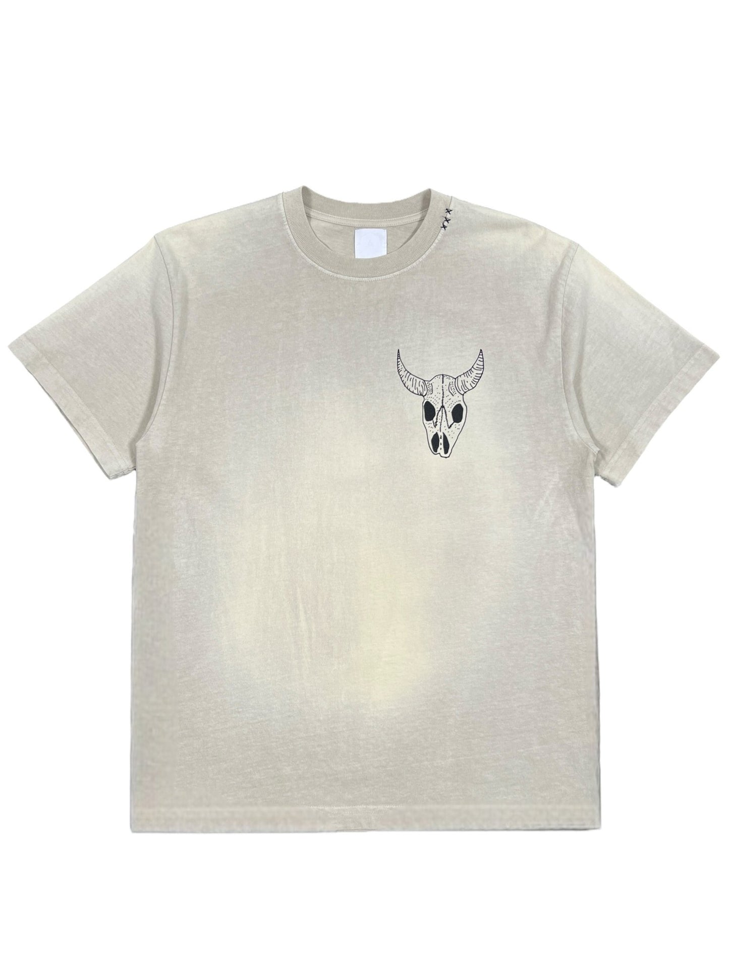 The ALCHEMIST LOST SKULL TEE JET STREAM by ALCHEMIST is a beige vintage washed short-sleeve T-shirt featuring a small bull skull graphic on the left chest area, crafted from 100% cotton for comfort and durability.