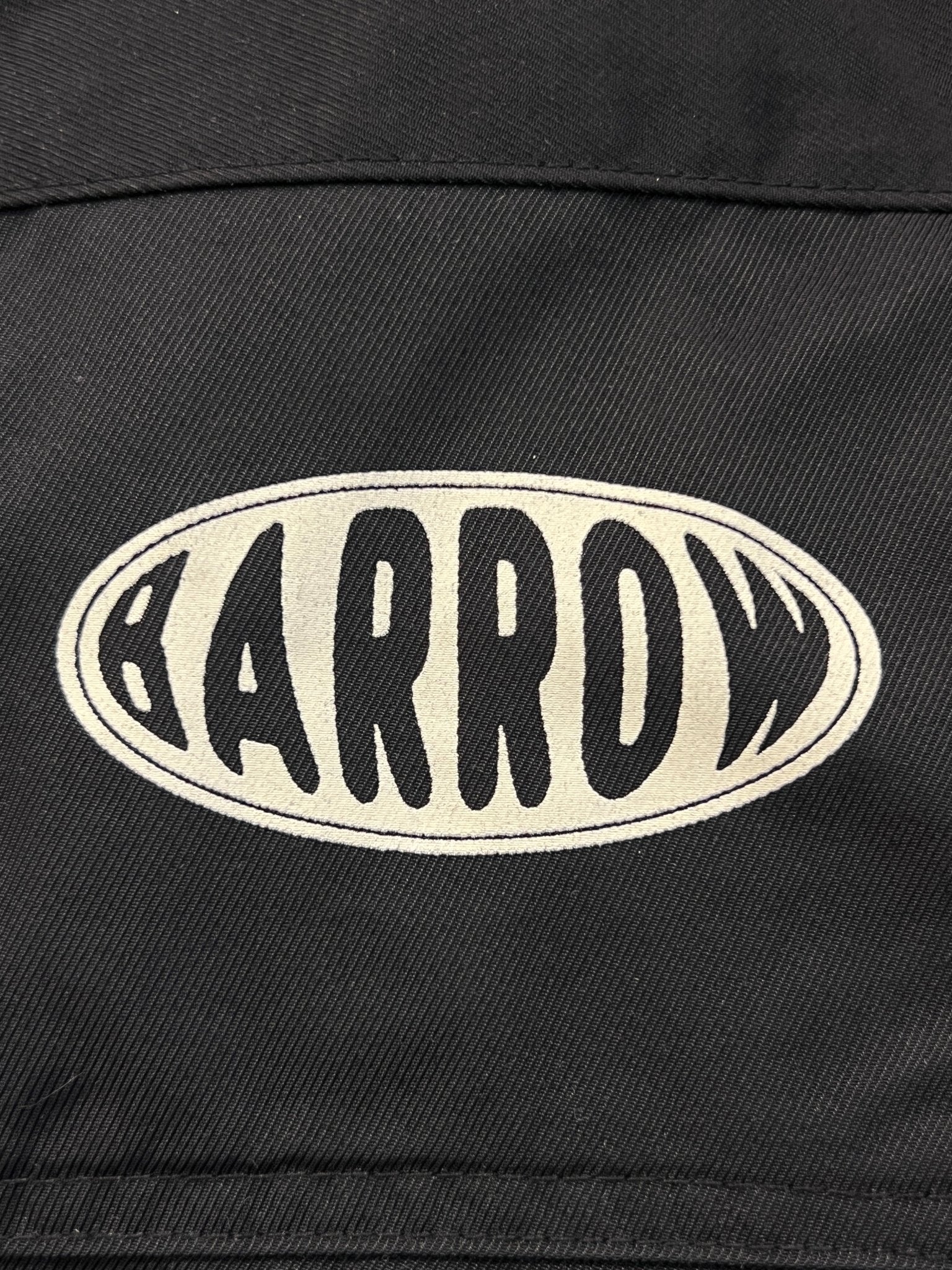 The Barrow S5BWUAJK065 Unisex Nylon Jacket in black features a bold back patch with "BARROW" in distorted white letters inside an oval—an urban-cool detail by BARROW.
