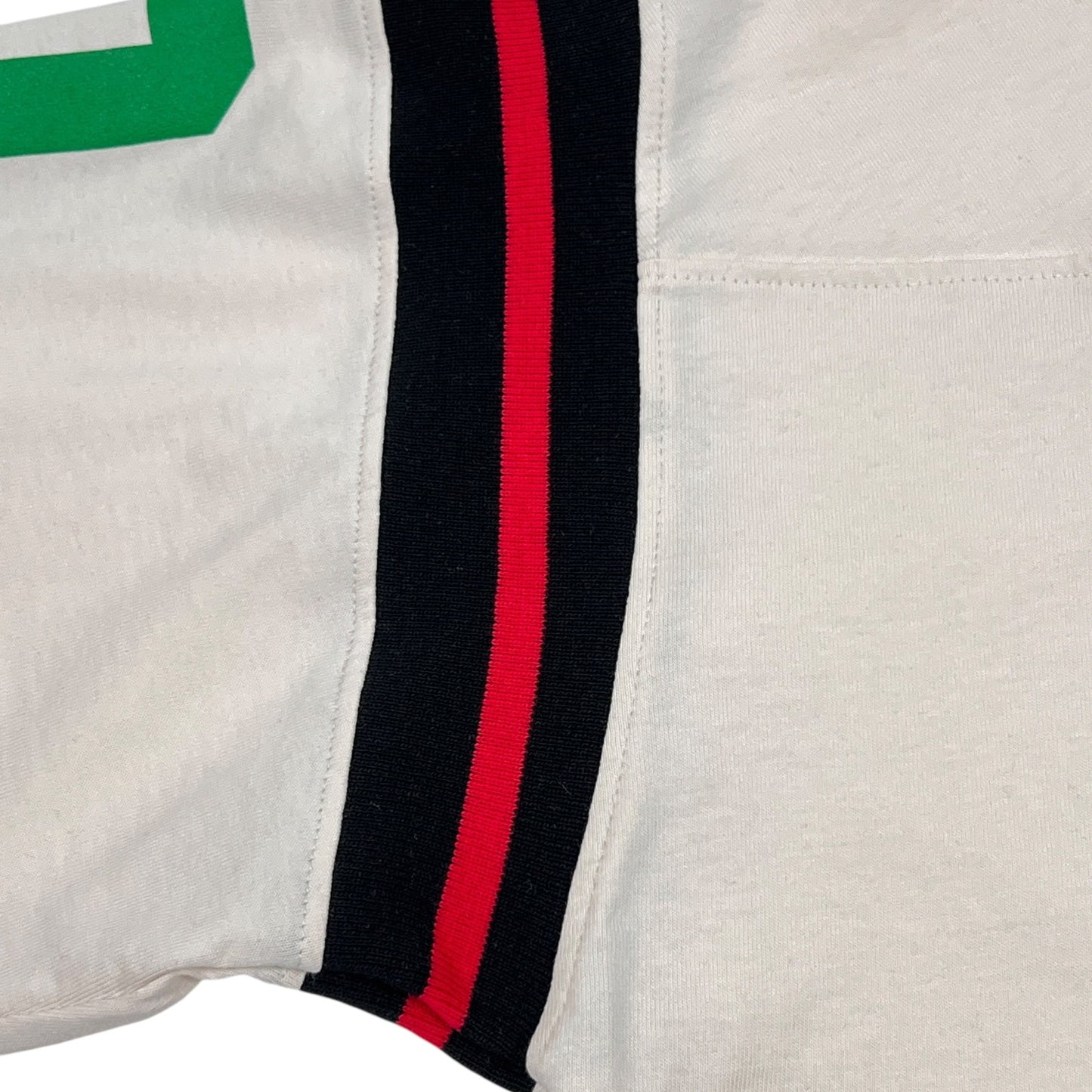 A close-up of the Barrow S5BWUATH032 Jersey T-shirt Vanilla by BARROW features a white design with green numbers, plus black and red striped side seams. Made from 100% cotton, it ensures comfort and style.