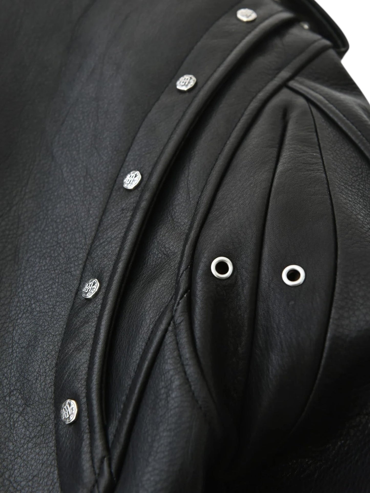 Close-up of the BIRTH OF ROYAL CHILD Birth Of Royal Child BC25SSJK09 Pin Detail Leather Jacket Black, showcasing premium black leather with silver snap buttons, metal eyelets, and detailed stitching for a textured look.