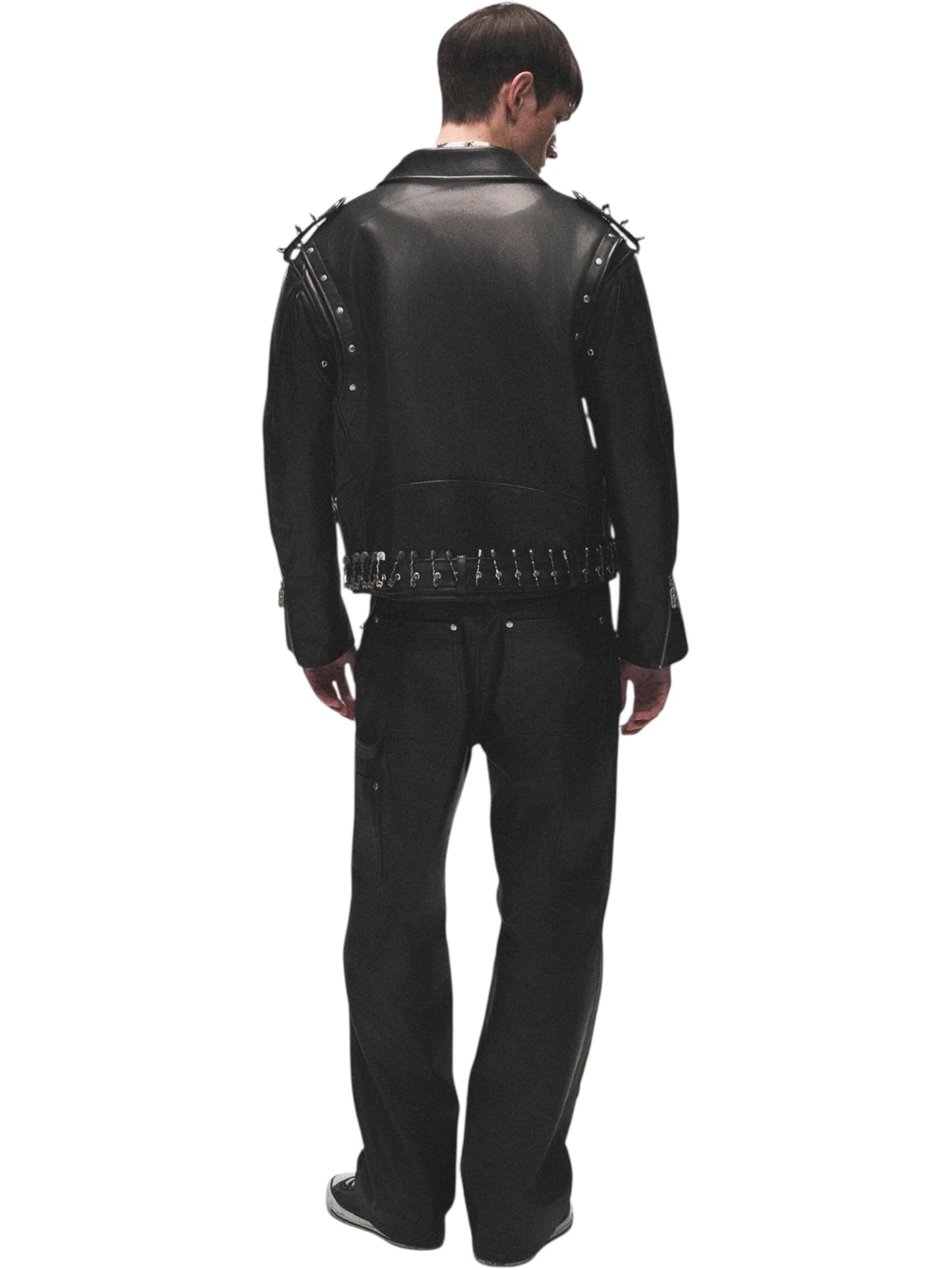 Person stands with their back to the camera, wearing the BIRTH OF ROYAL CHILD Birth Of Royal Child BC25SSJK09 Pin Detail Leather Jacket Black, a premium motorcycle-inspired leather jacket with spikes, paired with black pants.