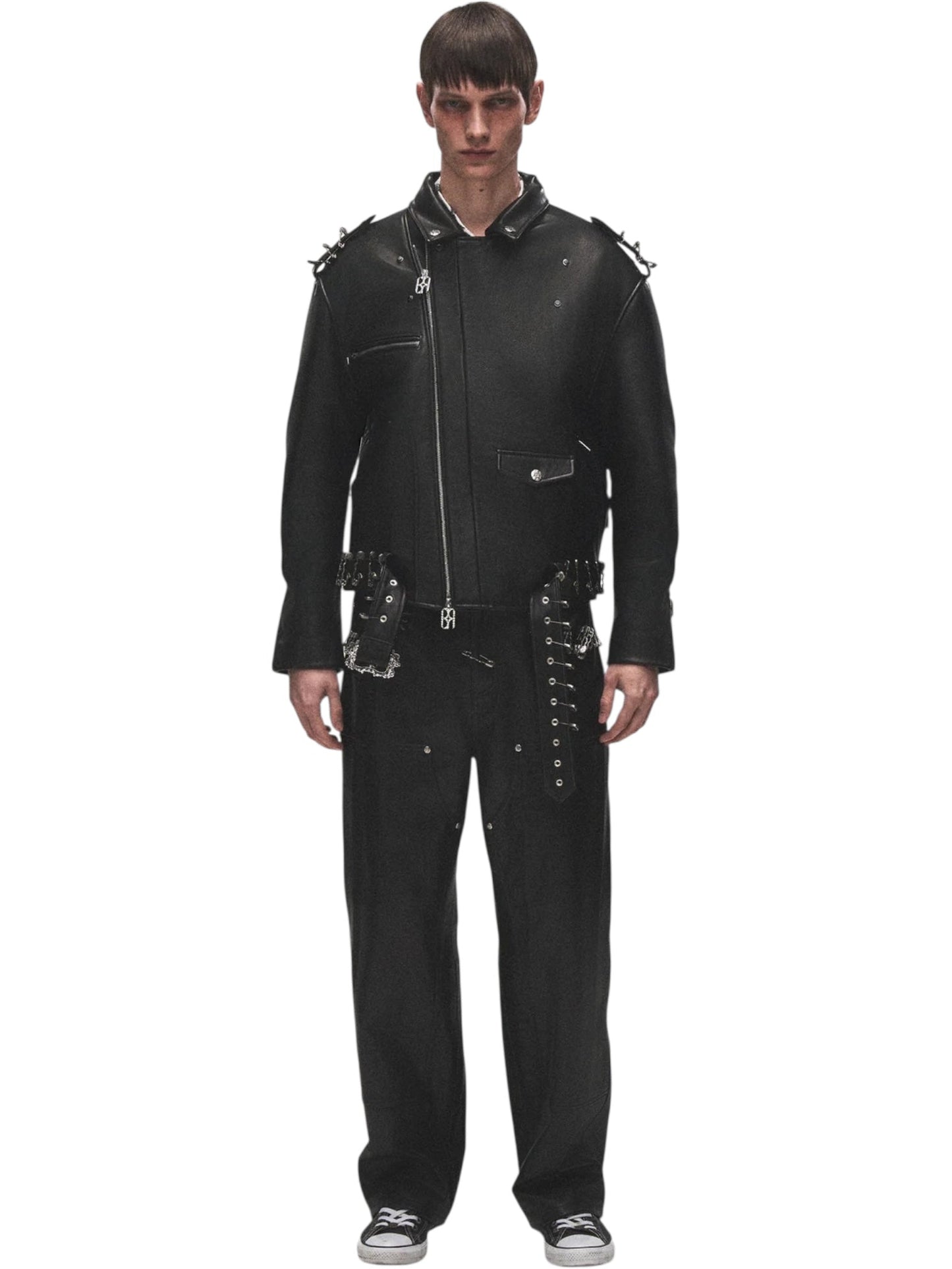 A man faces forward against a white background wearing the BIRTH OF ROYAL CHILD BC25SSJK09 Pin Detail Leather Jacket in black, styled with matching pants featuring zippers and buckles, and black sneakers.