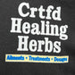 Close-up of a text design on a black, organic cotton CRTFD AYURVEDIC T-SHIRT by CRTFD that reads, "Crtfd Healing Herbs," followed by "Ailments * Treatments * Dosages" in smaller text below.