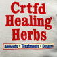 Close-up of a logo with red text reading "Crtfd Healing Herbs" on an organic cotton, beige CRTFD Ayurvedic T-Shirt Natural, and a blue section below listing "Ailments * Treatments * Dosages.