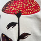 Close-up of a natural CRTFD FLY AGARIC T-SHIRT from CRTFD, featuring an abstract design with a red and yellow speckled mushroom and silhouetted leaves, crafted from 100% organic cotton.