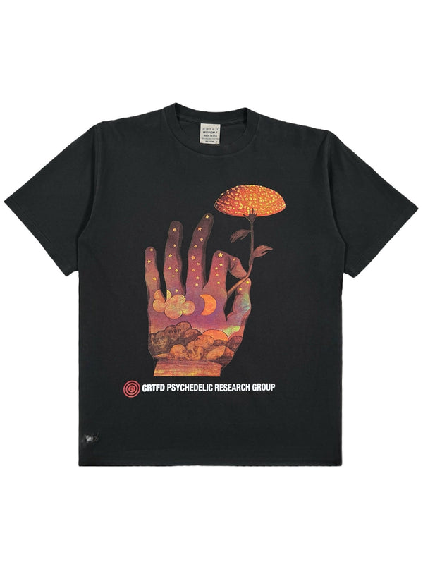 The CRTFD FLY AGARIC T-SHIRT VINTAGE BLK is a black T-shirt made from organic cotton, showcasing a colorful hand holding a mushroom and the text "CRTFD PSYCHEDELIC RESEARCH GROUP" underneath.