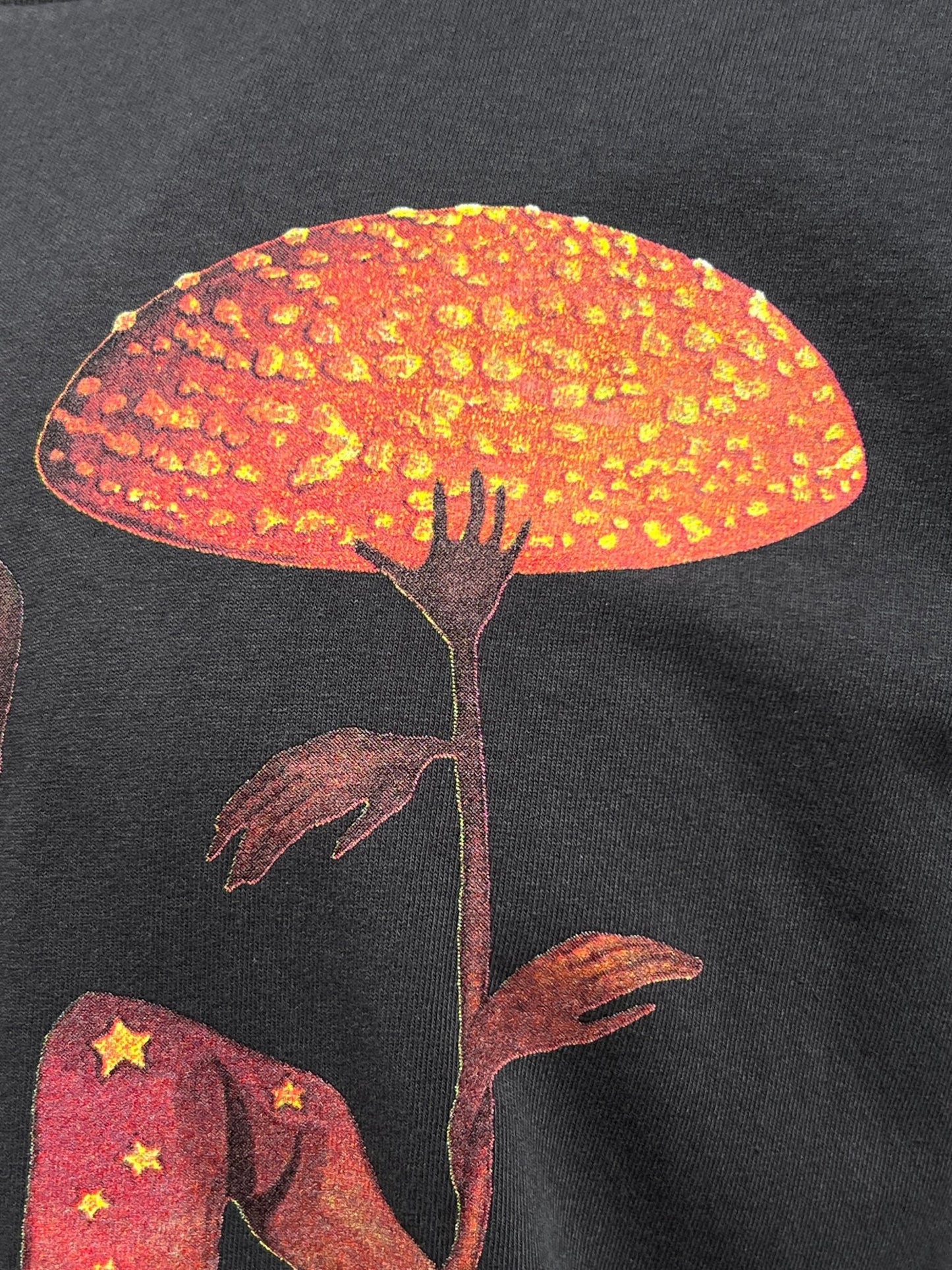 Get your hands on the CRTFD FLY AGARIC T-SHIRT VINTAGE BLK by CRTFD, showcasing a print of a humanoid figure with a mushroom cap as its head, set against a dark background and featuring vibrant orange and yellow hues. Crafted from soft organic cotton, this graphic tee is both eco-friendly and stylish.