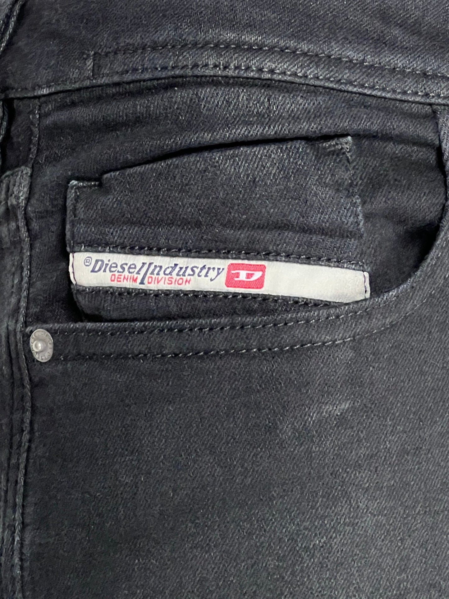 Close-up of a pocket on black stretch denim jeans with a visible label reading "DIESEL 1979 SLEENKER 9H94 DENIM BLACK by DIESEL Industry Denim Division.