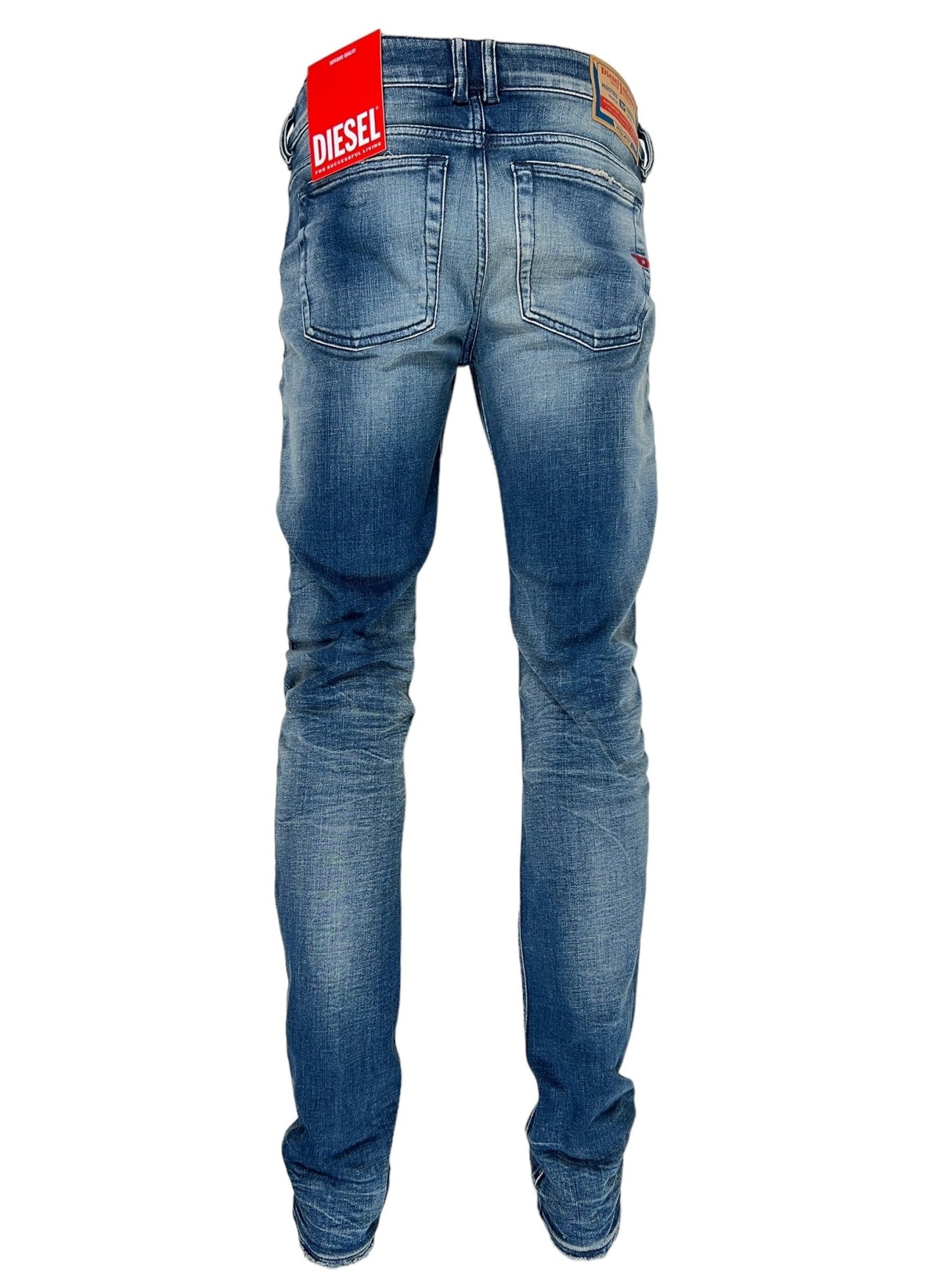 Back view of a pair of DIESEL 1979 SLEENKER 9J24 with tags attached. These Diesel jeans, made from medium blue stretch denim, feature faded details and visible back pockets, embodying a subtle punk-rock attitude.