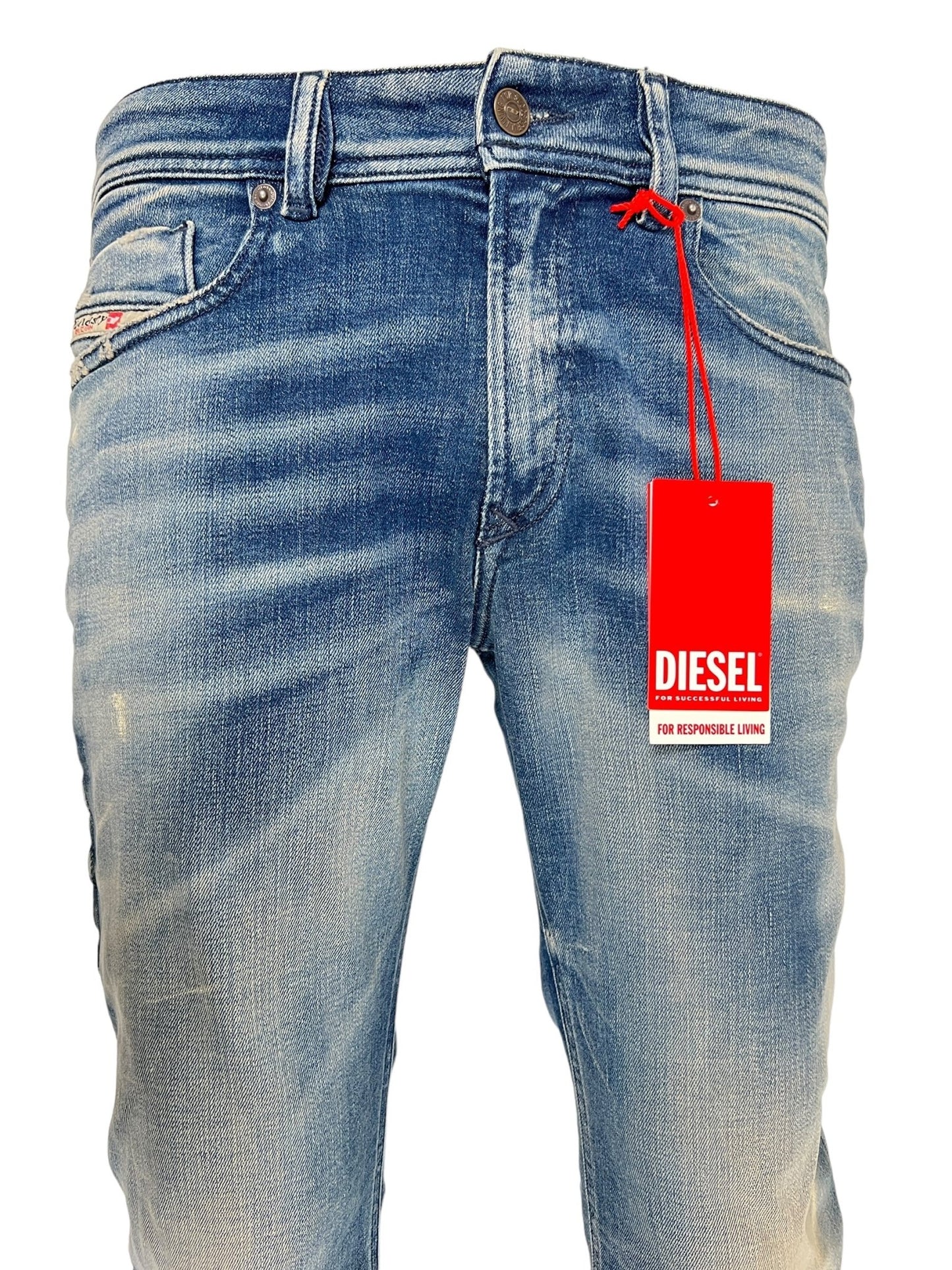 Close-up image of DIESEL 1979 SLEENKER 9J24 medium blue stretch denim jeans with a red tag attached near the waistband. The jeans feature a faded and distressed design, exuding a punk-rock attitude.