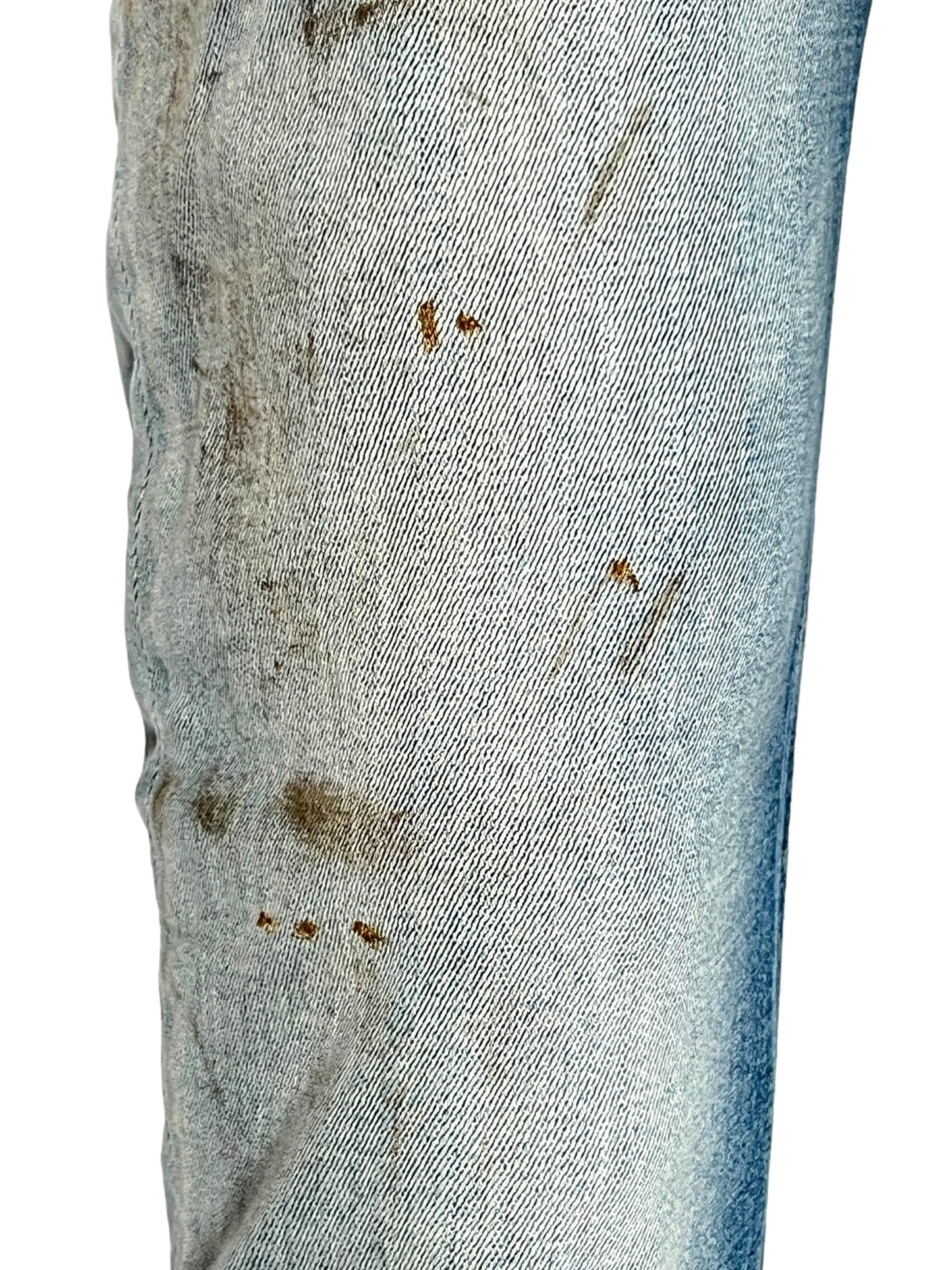 Close-up of the DIESEL 1979 SLEENKER 9J25, a pair of blue skinny jeans from DIESEL made from organic cotton denim, with visible dirt and stains on the fabric, particularly on the thigh and knee areas.