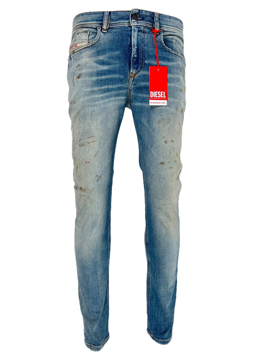 A pair of DIESEL 1979 SLEENKER 9J25 blue organic cotton denim jeans featuring a red Diesel tag, displaying signs of wear and slight distressing on the fabric for that perfect punk-rock style.