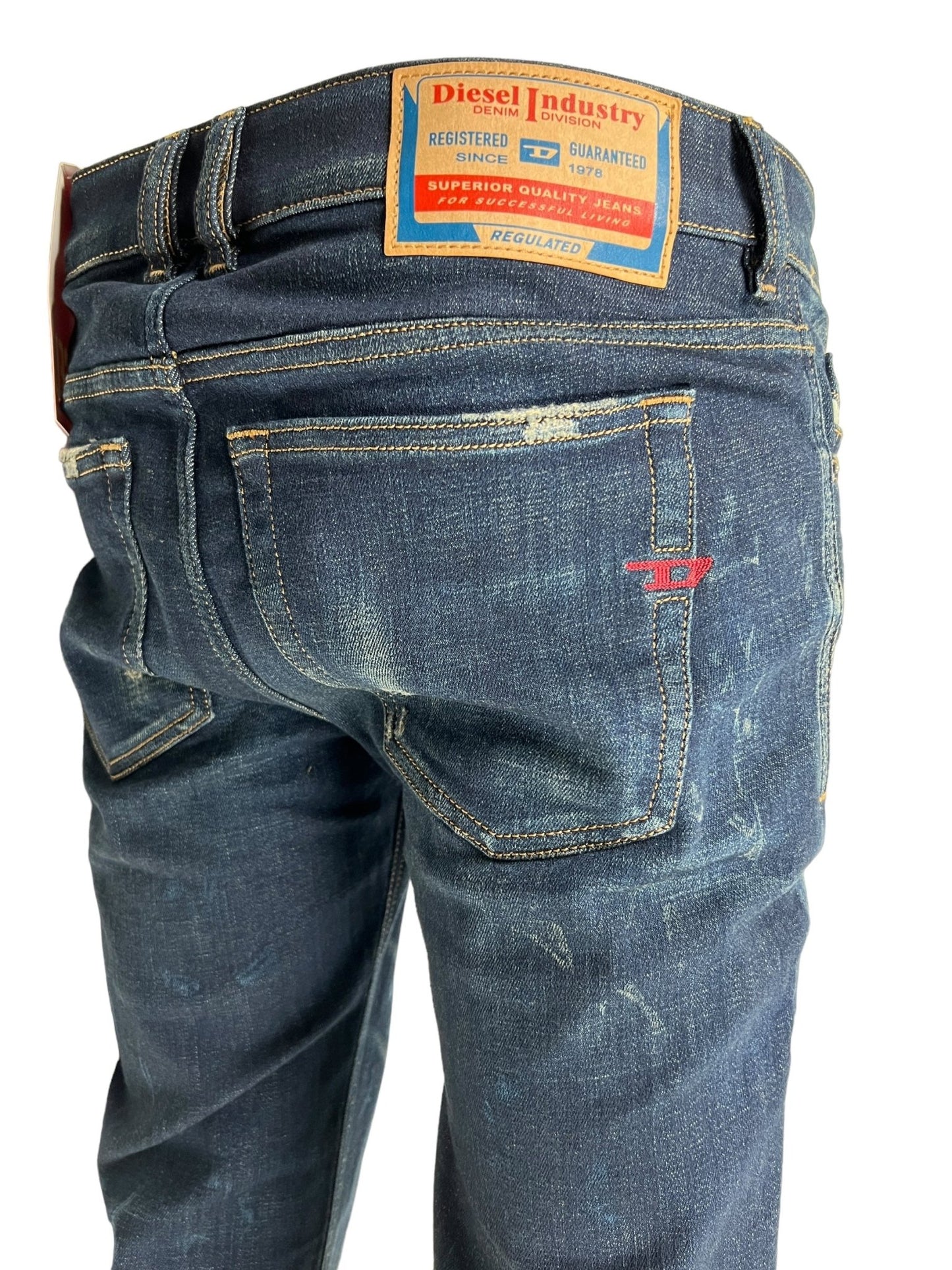 Close-up of the back of a pair of DIESEL 1979 SLEENKER 9J26 blue skinny jeans, showcasing the detailing on the pockets and a label on the waistband highlighting DIESEL's brand quality. The low waist design complements the zip fly for a modern fit.