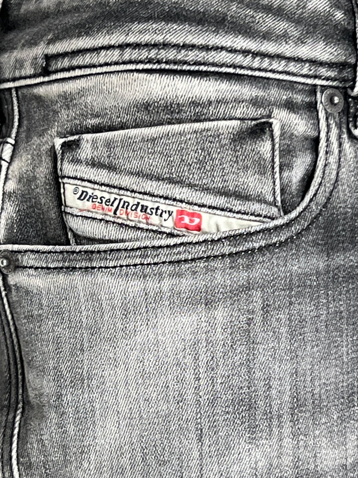 A close-up of a faded grey denim pocket features a small label with "DIESEL," embodying the trendy skinny fit style of the Diesel 1979 Sleenker 9J28.