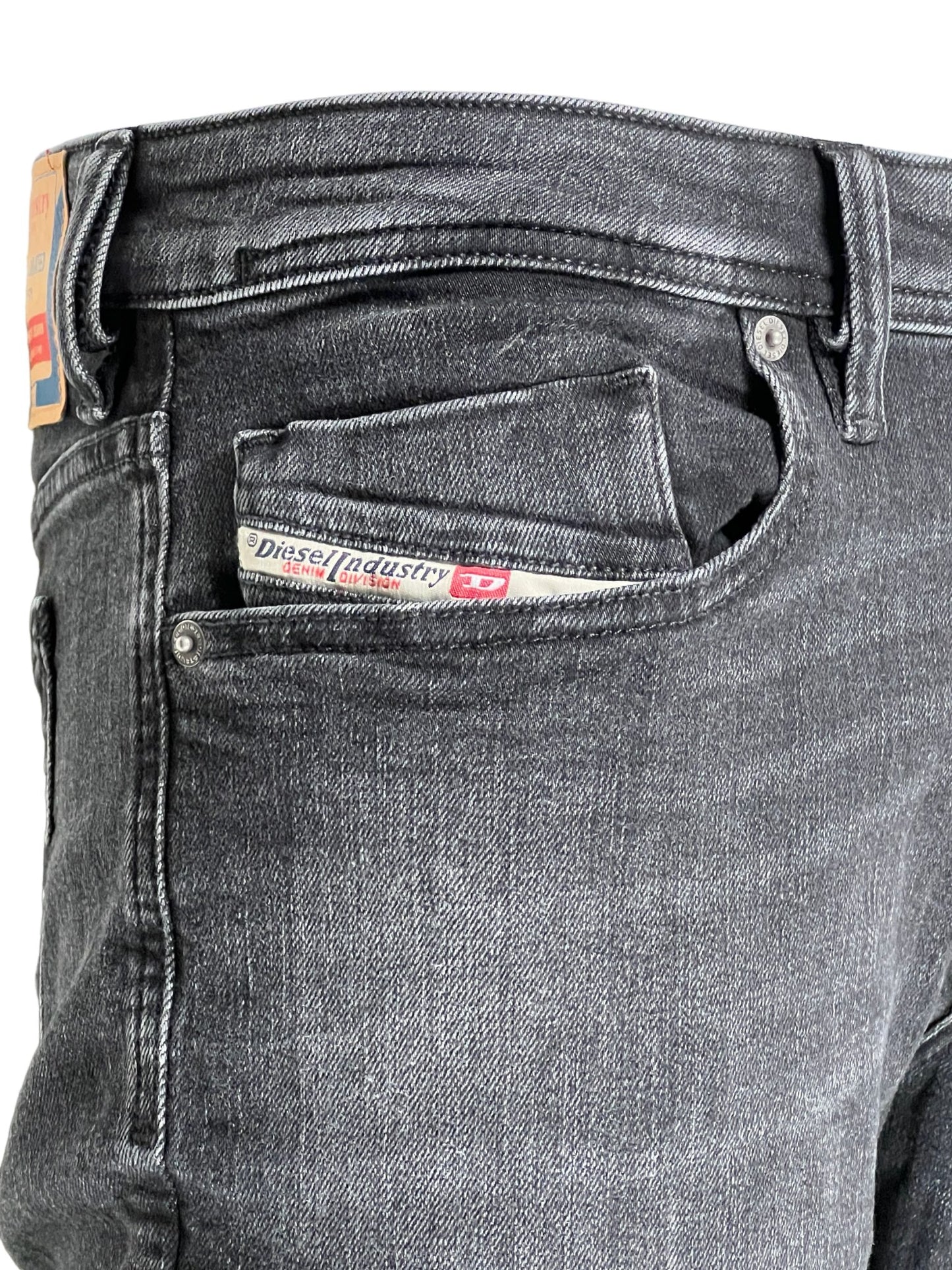 Close-up of black stretch denim jeans with a DIESEL 1979 SLEENKER PFAX brand label on the pocket.
