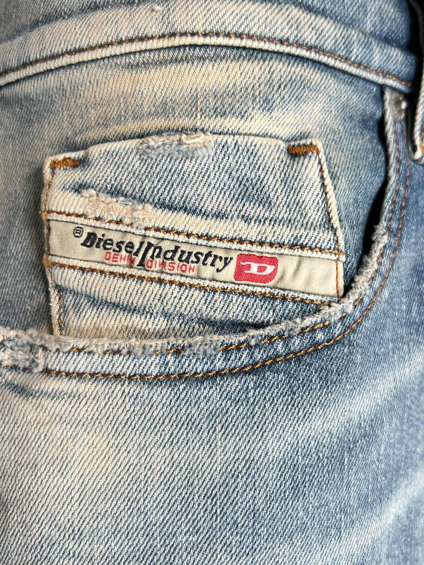 Close-up of a worn denim slim jeans back pocket with a visible DIESEL label above it, crafted from organic cotton, featuring the DIESEL 2019 D-STRUKT 07V8 design.