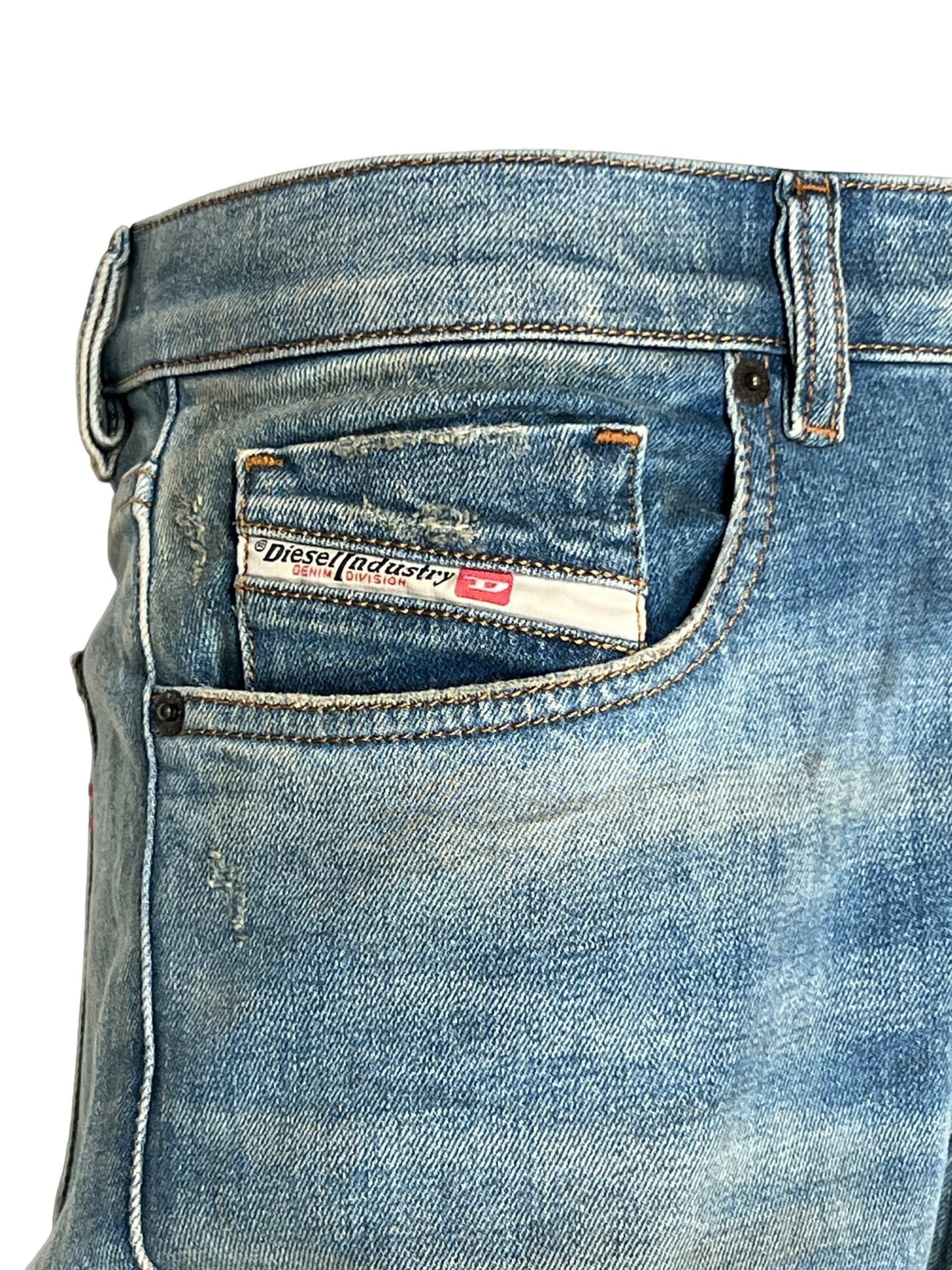 Close-up of a pair of DIESEL 2019 D-STRUKT 9H50 DENIM made from recycled cotton with a visible label inside the small front pocket. The jeans, crafted using waterless technology, feature slight wear and tear.