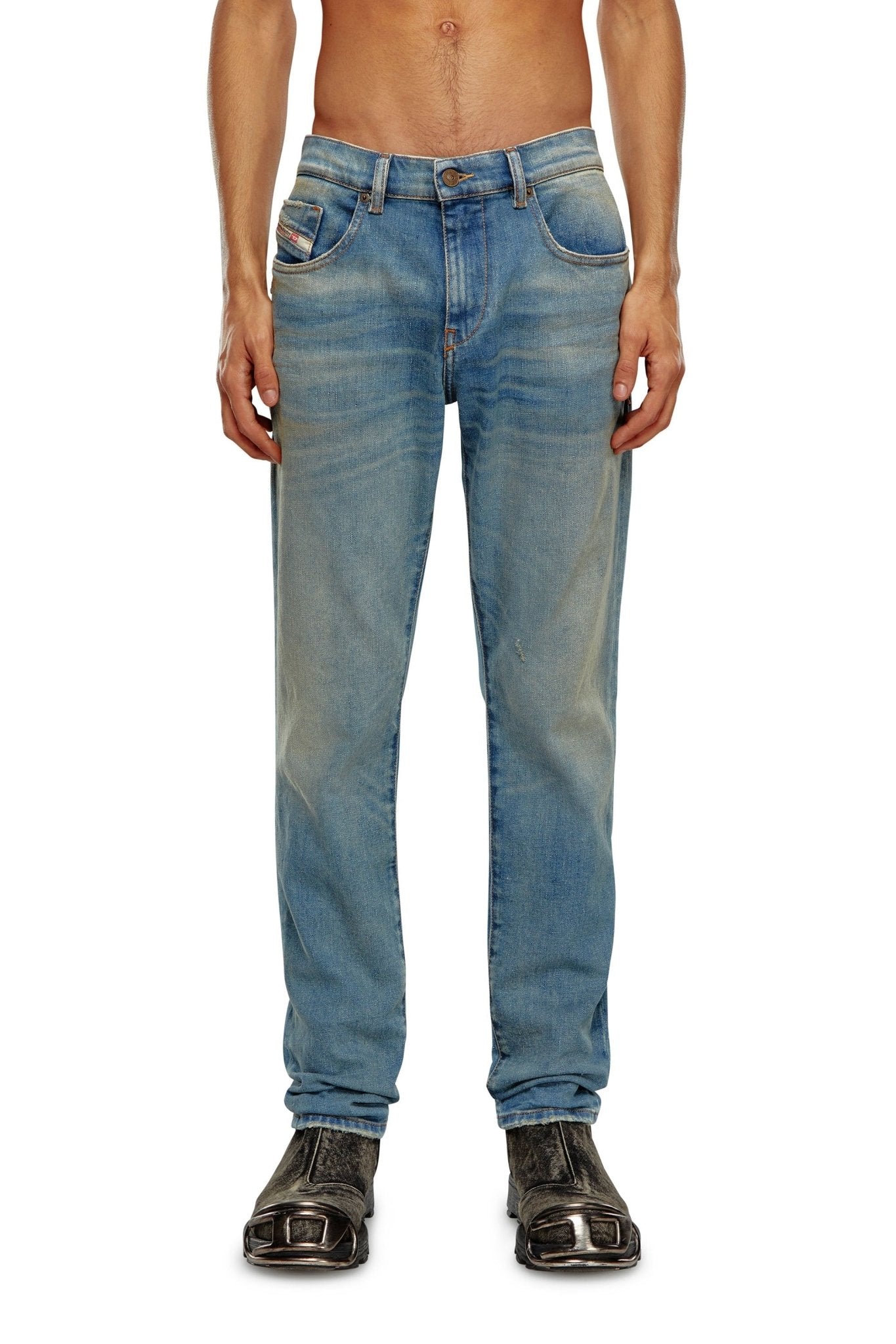 Man wearing light blue, slightly faded DIESEL 2019 D-STRUKT 9H50 DENIM jeans made from recycled cotton and black, square-toed shoes, with no shirt visible in the frame.