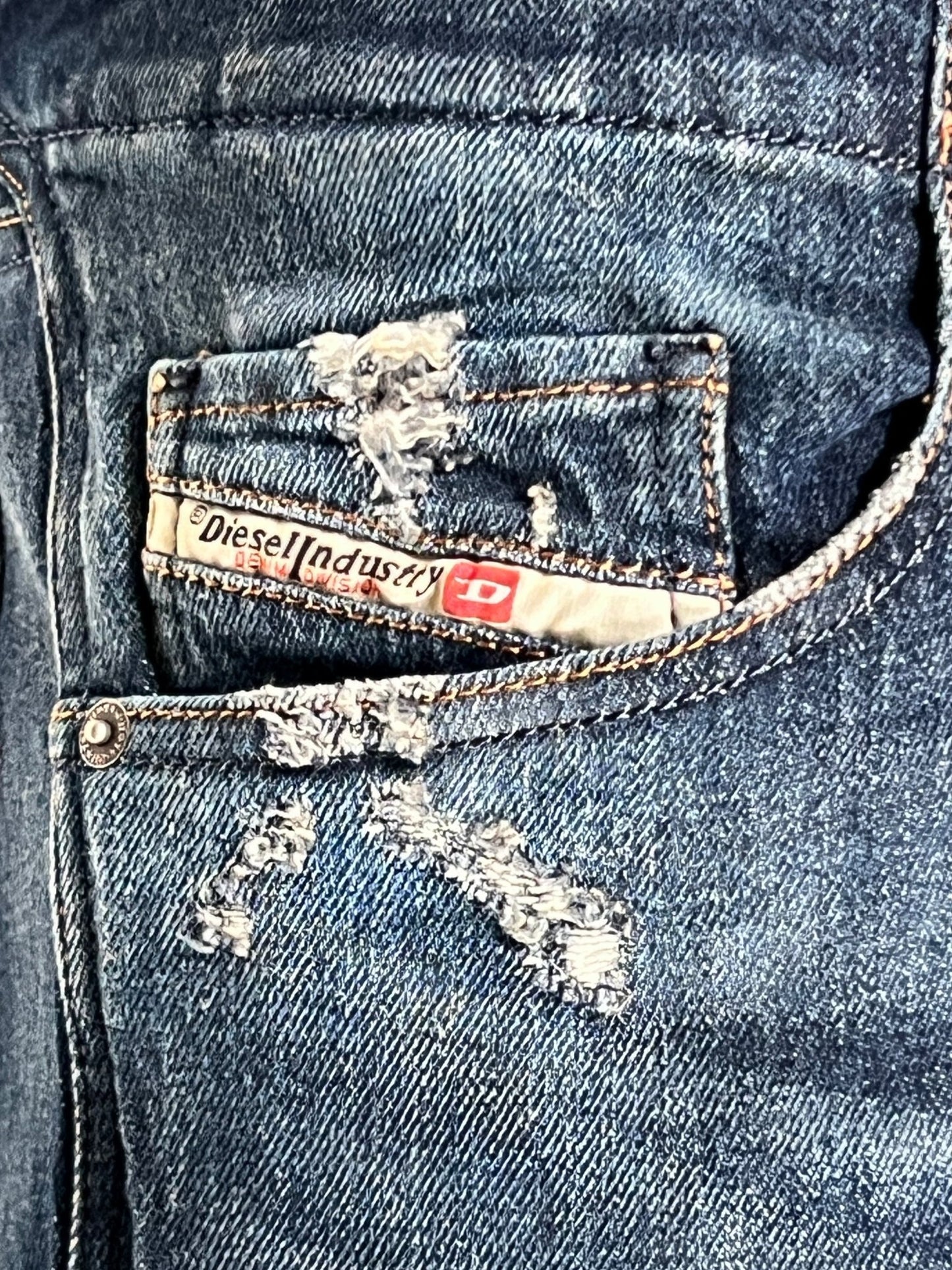 Close-up of a torn denim pocket with a label reading “DIESEL,” showcasing the essence of Diesel DNA found in the Diesel D-Backler 9J56.