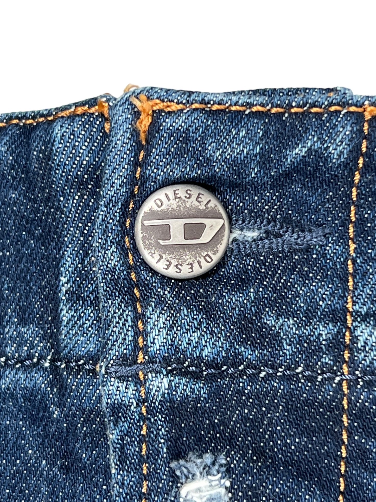 A close-up of a metal button on the Diesel D-Backler 9J56 Bootcut jeans, featuring "Diesel" engraved on it, perfectly embodies DIESEL's signature style. The orange stitching enhances the character of the comfortable denim fabric.