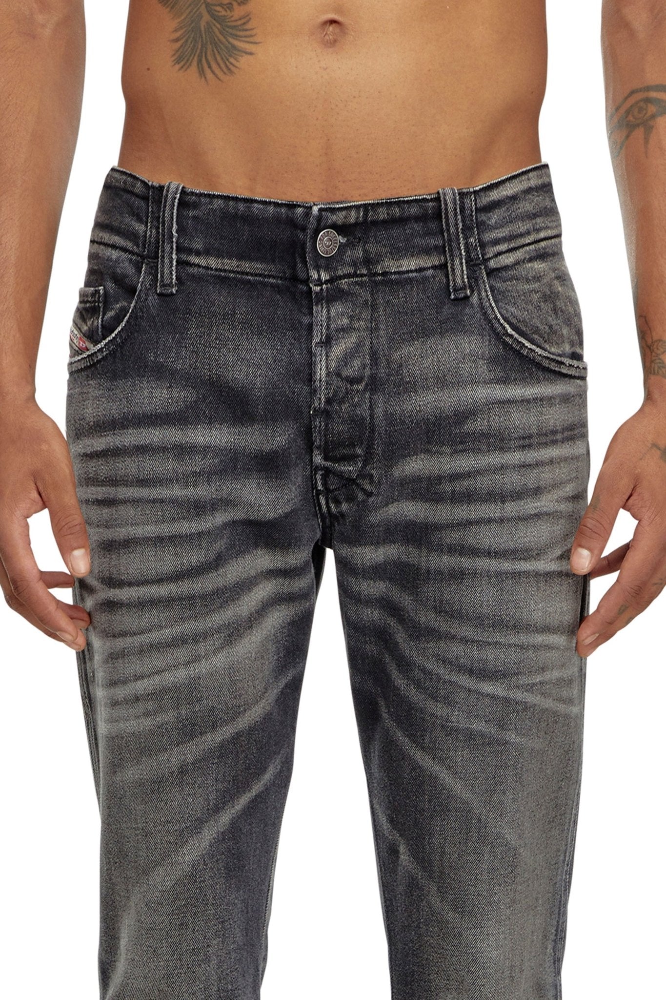 A person wearing the DIESEL D-BACKLER-RR 9J65 distressed dark-wash bootcut jeans with a tattoo visible on the torso. The image is cropped to show from the waist down to the upper thigh.