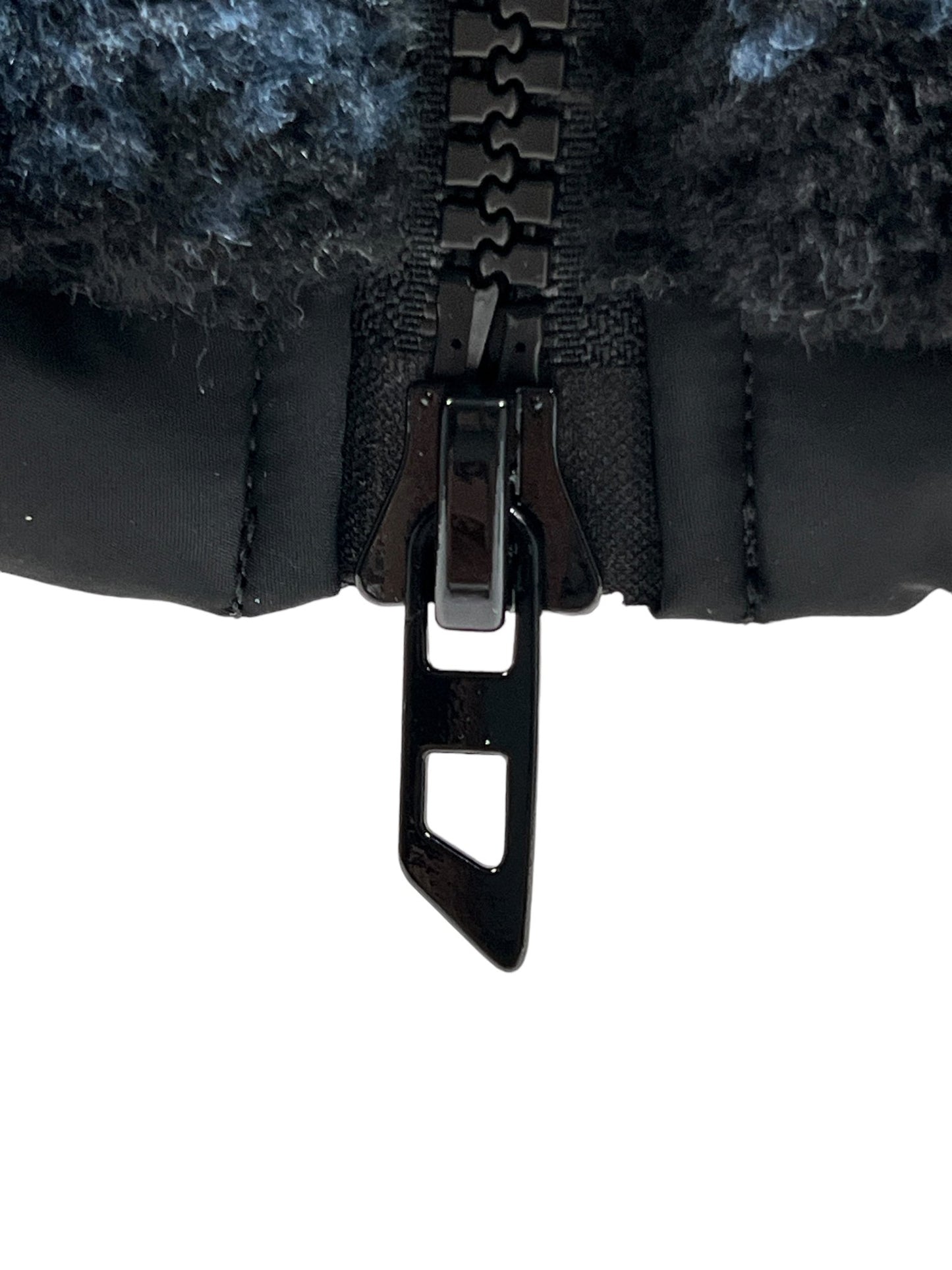 Close-up of a partially zipped black zipper on a dark textured fabric, showing the zipper pull and teeth of a DIESEL S-BERTO-TEDDY BLACK jacket.