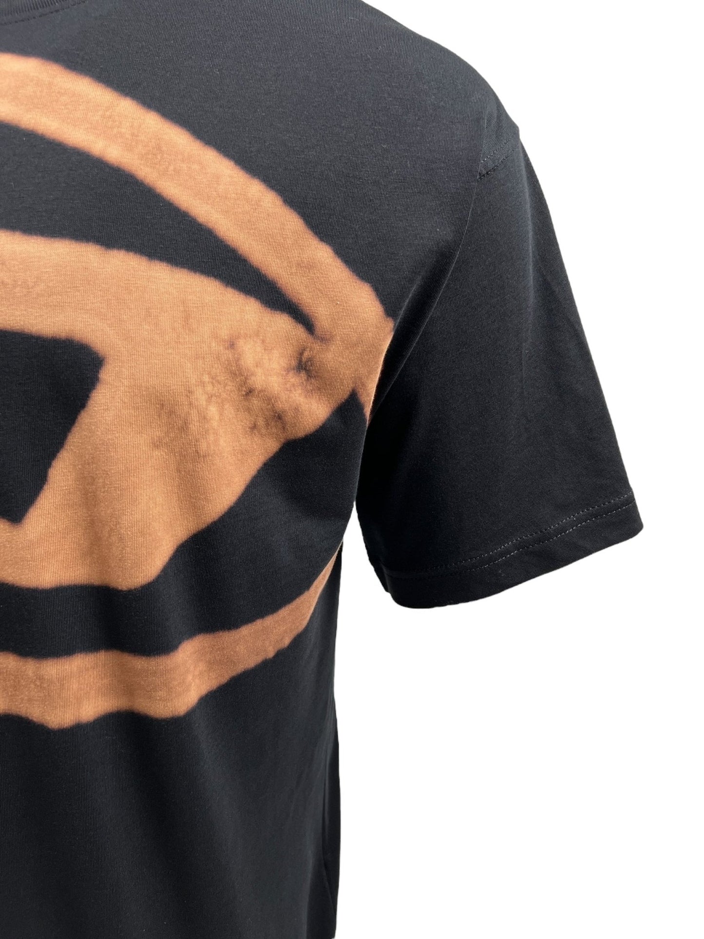 Close-up of the DIESEL T-BOXT-BLEACH T-SHIRT BLACK from DIESEL, made from organic cotton. The men’s black T-shirt showcases a large tan abstract design, with focus on the sleeve and upper side of the garment against a white background.