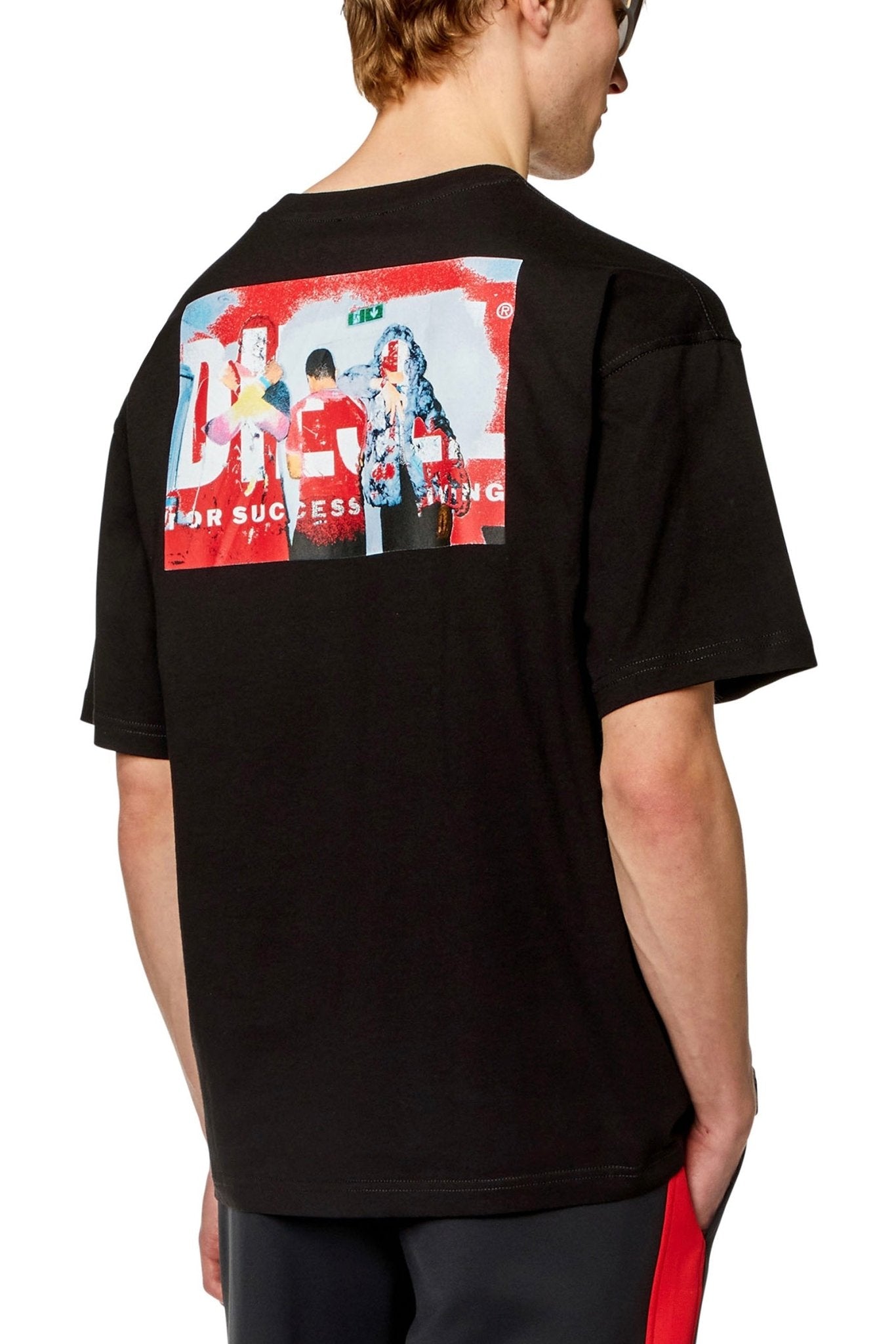 A man wearing a Diesel T-BOXT-N11 T-shirt in black cotton jersey with a Diesel logo graphic print on the back.