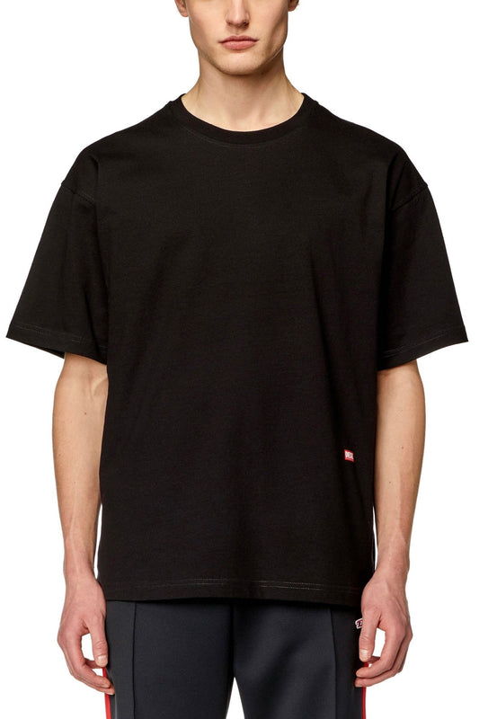 Man wearing a DIESEL T-BOXT-N11 T-SHIRT BLACK, men's relaxed-fit T-shirt standing against a neutral background.