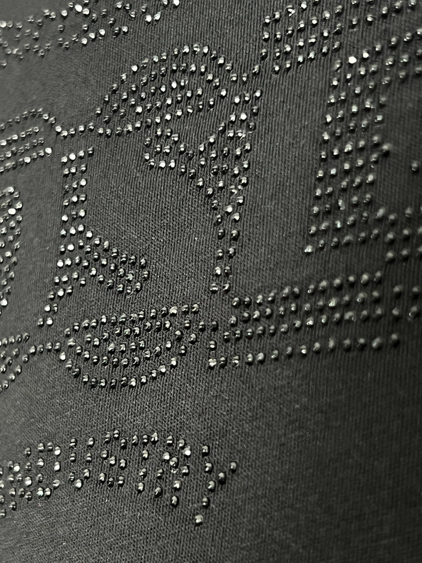 Close-up image of the DIESEL T-BOXT-SIDE T-SHIRT BLACK, made from 100% cotton, showcasing embossed, raised dot patterns that create an abstract design and studded logo text.