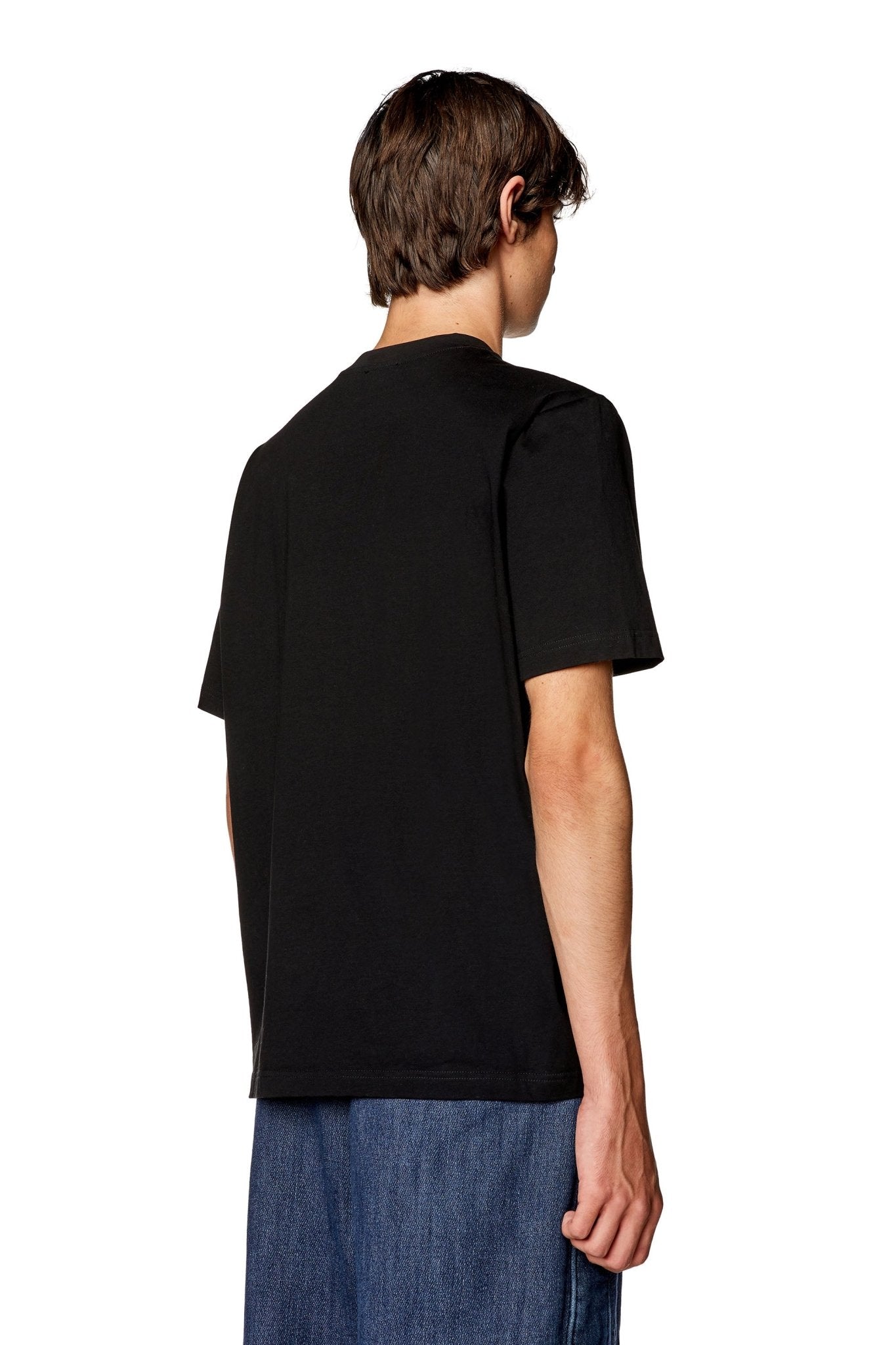 A person is standing with their back turned, wearing a black Diesel T-Just-Microdiv T-Shirt and blue jeans.