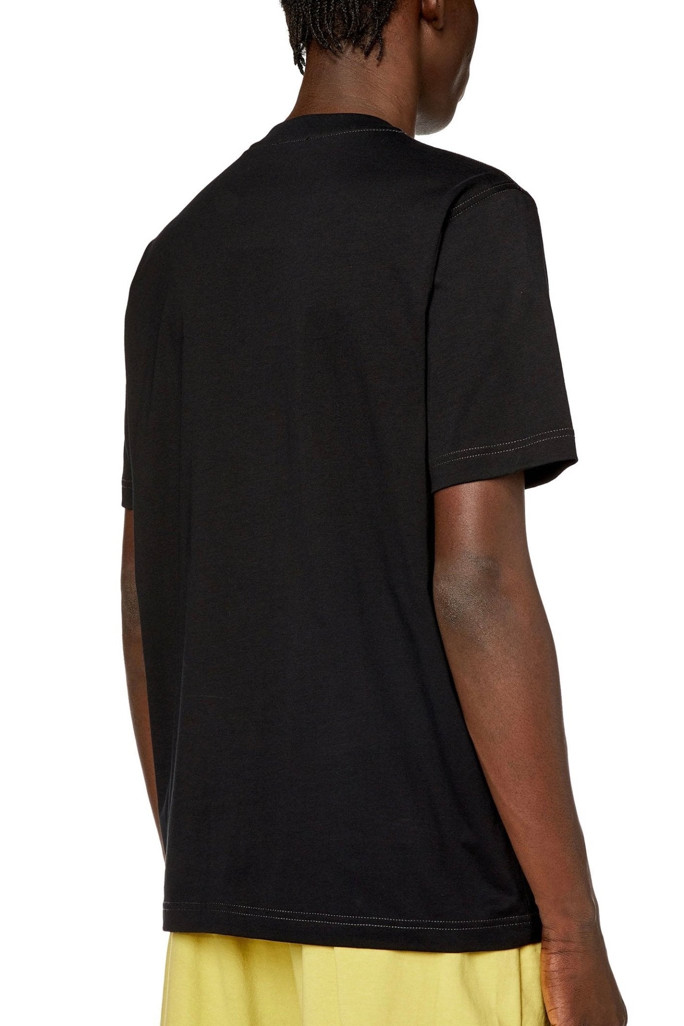Person wearing a Diesel DIESEL T-JUST-N12 black organic cotton jersey men's T-shirt viewed from the back.