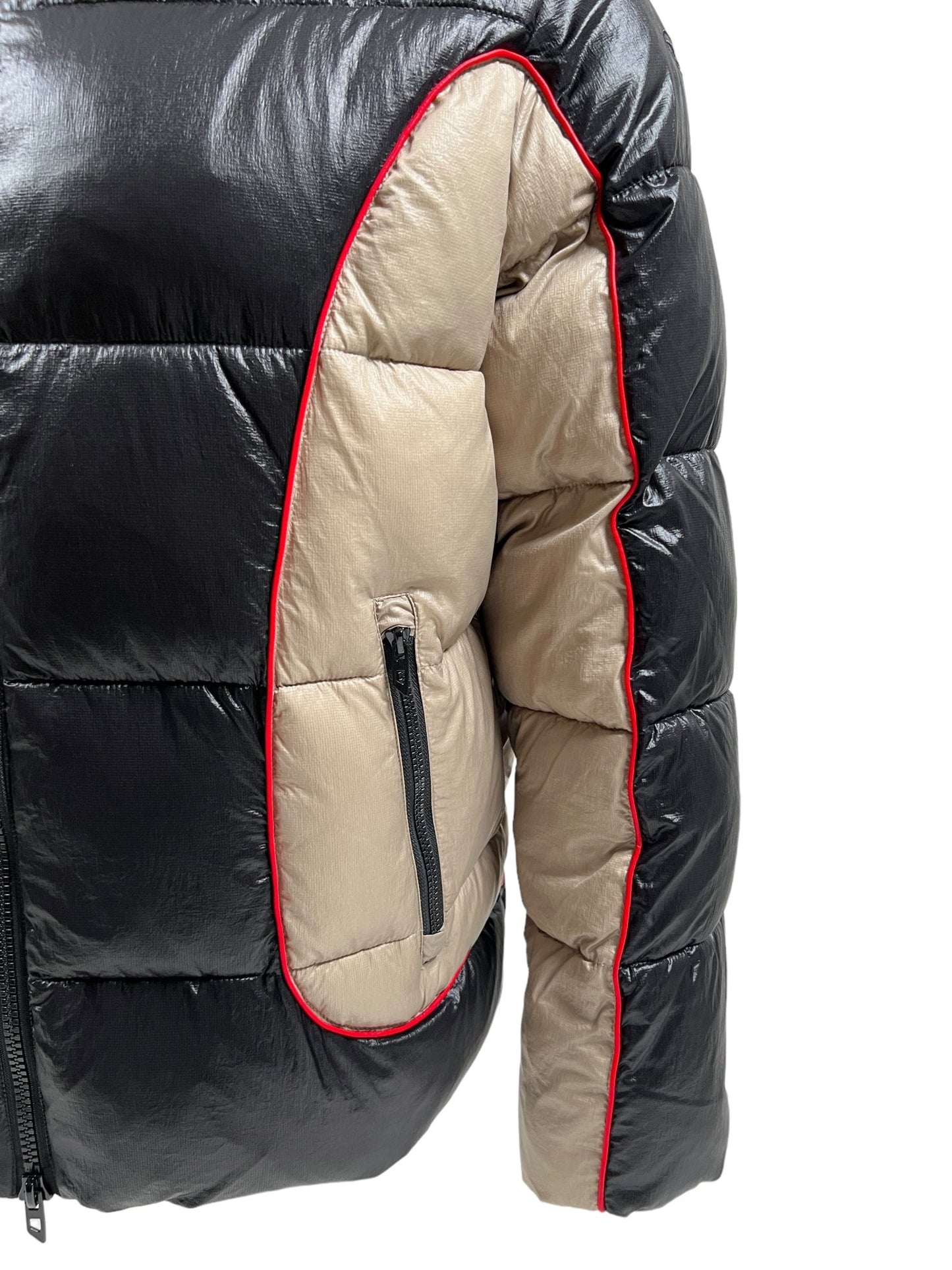 Close-up of the DIESEL W-OSTEND JACKET BLACK showcasing black and beige panels with red piping along the seams and a small zippered pocket on the beige section. The panelled design adds a stylish touch to this eco-friendly piece made from recycled polyester by DIESEL.