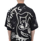 A person with a shaved head is wearing a DOM REBEL Domrebel Chained Shirt in black, which boasts a large abstract, cartoonish graphic design and graffiti elements on the back, made from a soft rayon Tencel blend.