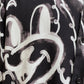 Close-up of a DOM REBEL DOMREBEL CHAINED SHIRT BLACK with a black all-over print featuring a white graffiti-style drawing of a cartoon face. The design showcases large eyes and a wide smile, bringing playful charm to the rayon Tencel blend fabric.