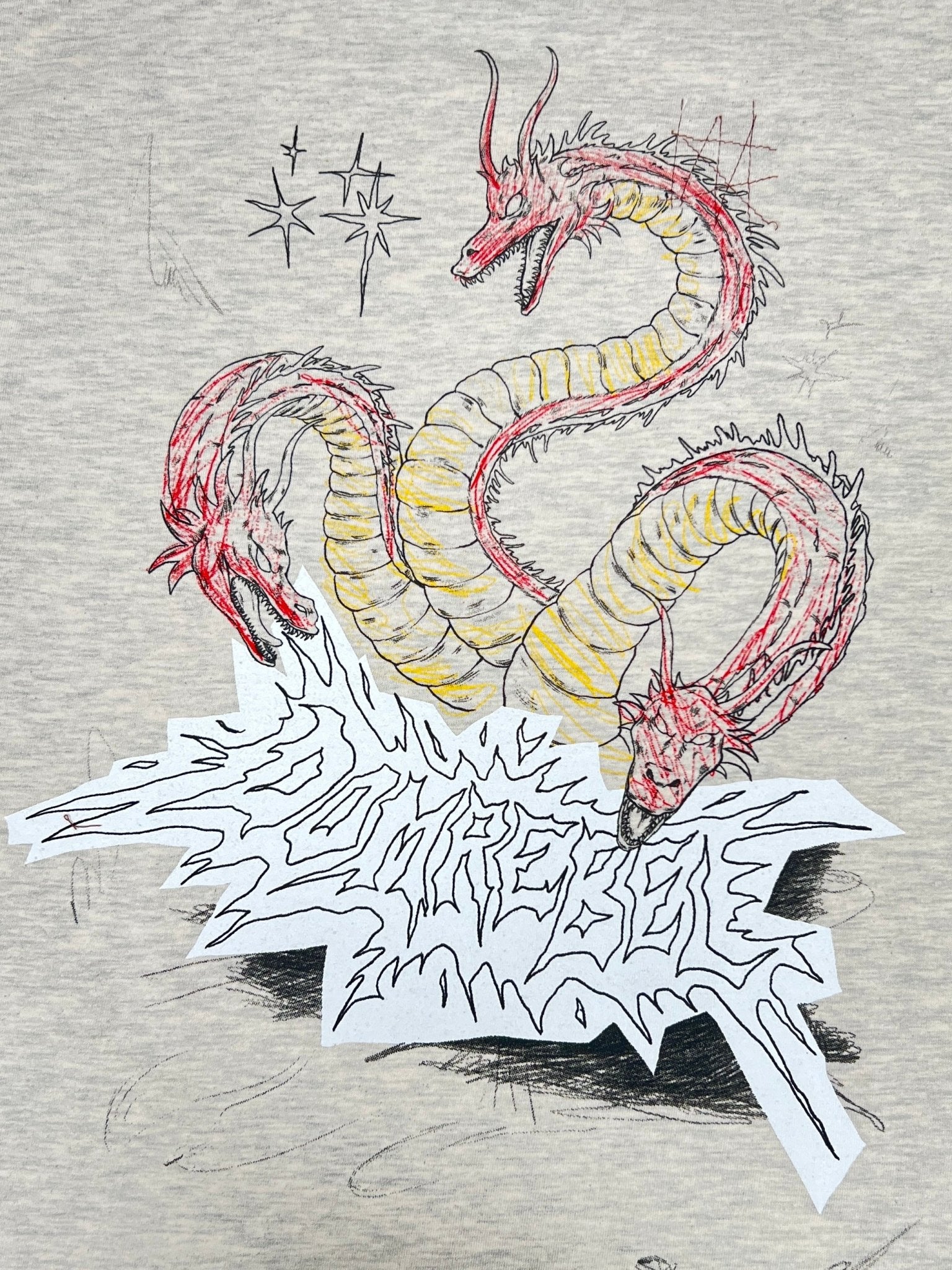 The Domrebel Conflict T-shirt Greige by DOM REBEL showcases an original doodle of a three-headed dragon in red accents with "CONCRETE" text and sparkles, creating a standout piece for any collection.