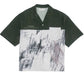 The Domrebel Demi Camp Collar Shirt by DOM REBEL features a white twill base with dark green shoulders, adorned with abstract black and gray sketches.