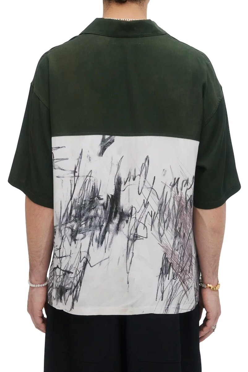 A person wearing the Domrebel Demi Camp Collar Shirt Green by DOM REBEL, featuring a twill fabric with a dark green top and an abstract black-and-white lower design, seen from the back.