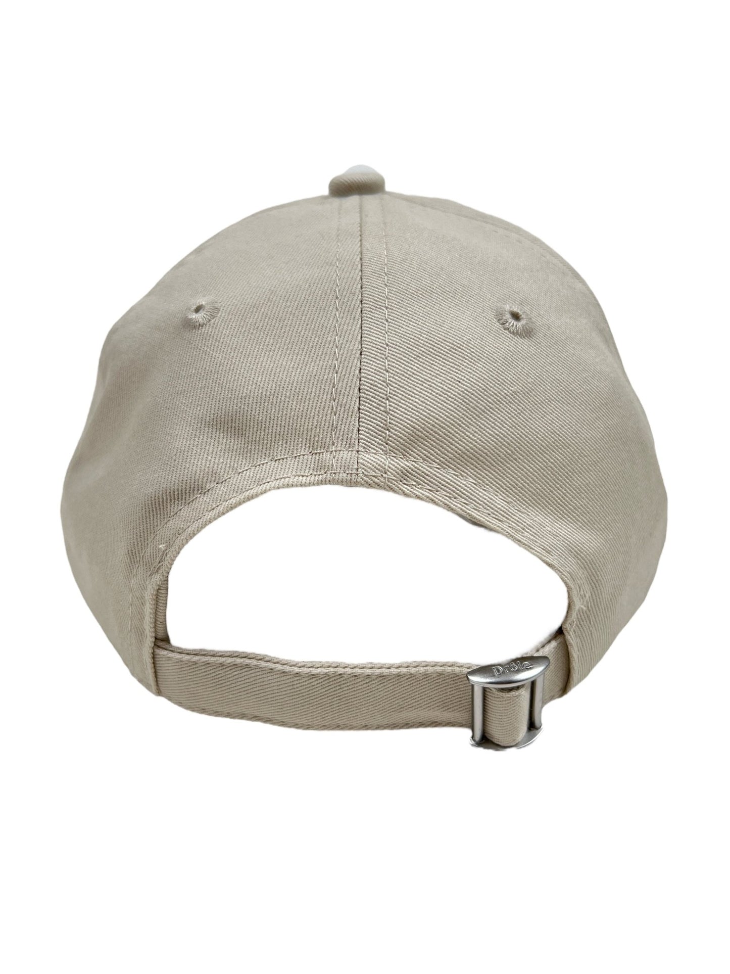 Back view of the DROLE DE MONSIEUR CP151-CO138-MT LA CASQUETTE SLOGAN MASTIC, a beige cotton baseball hat featuring an adjustable strap and buckle, subtly embroidered with 'Not From Paris Madame'.