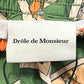 Clothing label with the text "DROLE DE MONSIEUR" attached to mid-length swim shorts featuring a card game print. (Product Name: DROLE DE MONSIEUR D-BS141-PL136 LE SHORT PLAGE JEU DE CARTES GN)