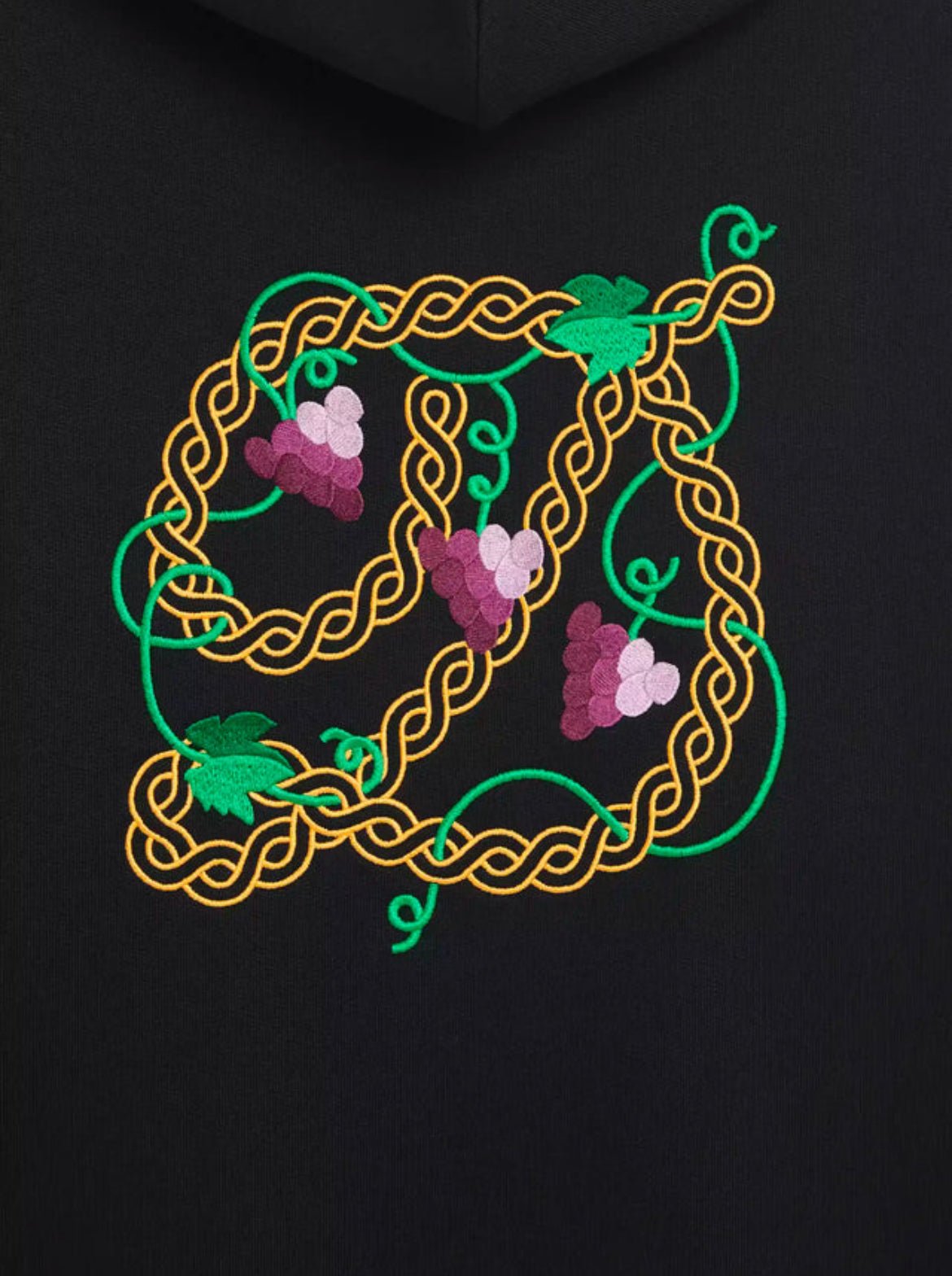 A black French terry hoodie named DROLE DE MONSIEUR E-HO170-CO127-BL LE HOODIE RAISIN BLK from the brand DROLE DE MONSIEUR, featuring an embroidered design with three clusters of grapes surrounded by intertwined yellow and green vines.