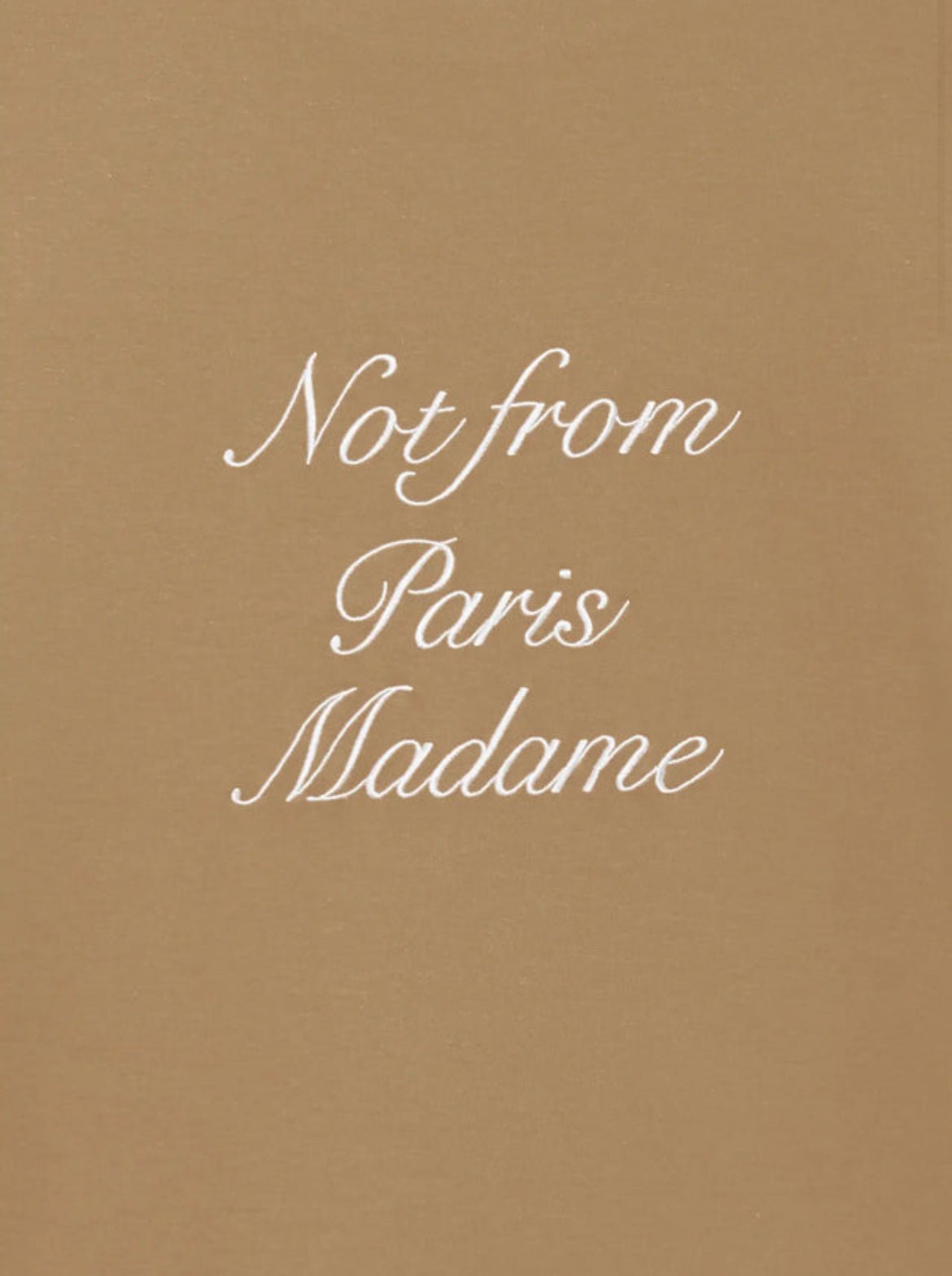 A beige cotton t-shirt from DROLE DE MONSIEUR, featuring the cursive text "Not from Paris Madame" elegantly written in white.