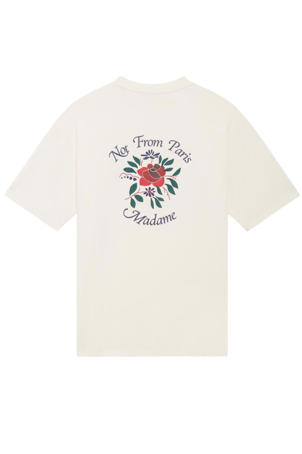 A white cotton T-shirt from DROLE DE MONSIEUR, model E-TS210-CO002-CM Le T-Shirt Cream, with a ribbed neckline and a design on the back featuring a red flower and green leaves, accompanied by the slogan "Not From Paris Madame.