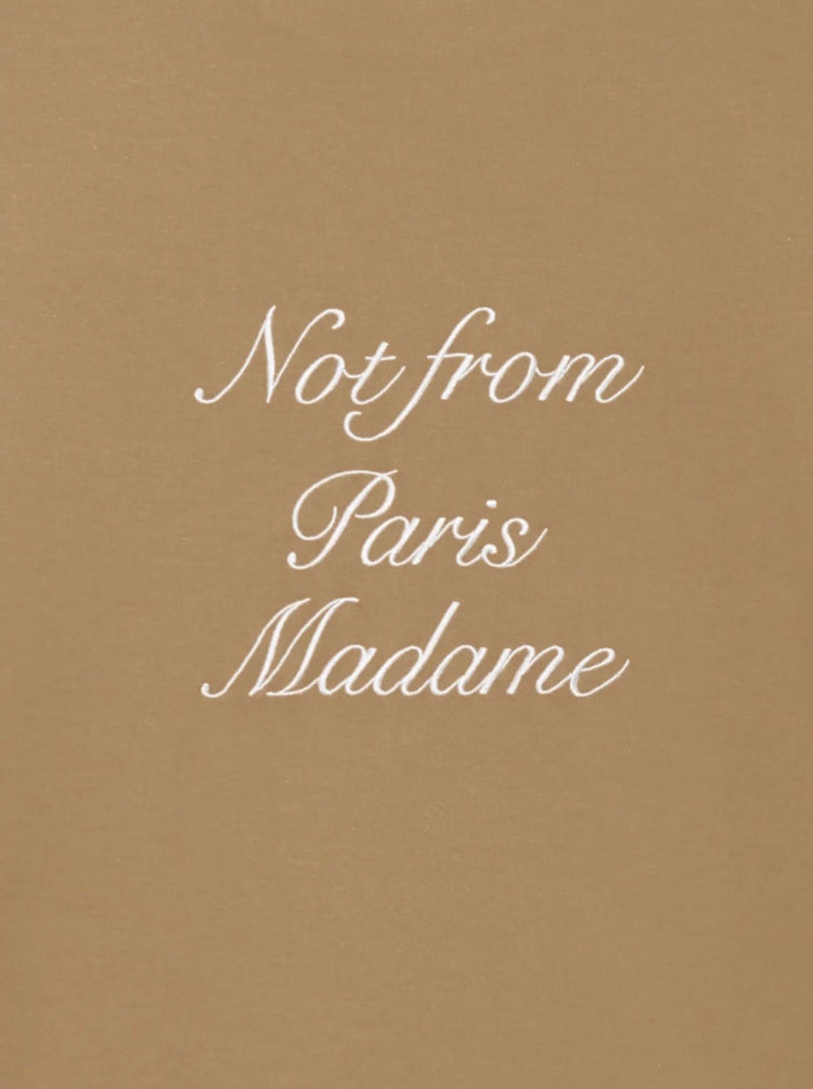 The text on a beige background says, "Not from Paris Madame" in an elegant white script font, echoing calligraphy-style artwork, as featured on the Drôle de Monsieur E-TS220-Co002-LBN Le T-Shirt Brw by Drôle de Monsieur.